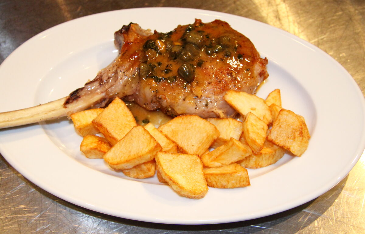 Veal Chops with Capers and Cornichons served on a white plate with roasted potatoes alongside