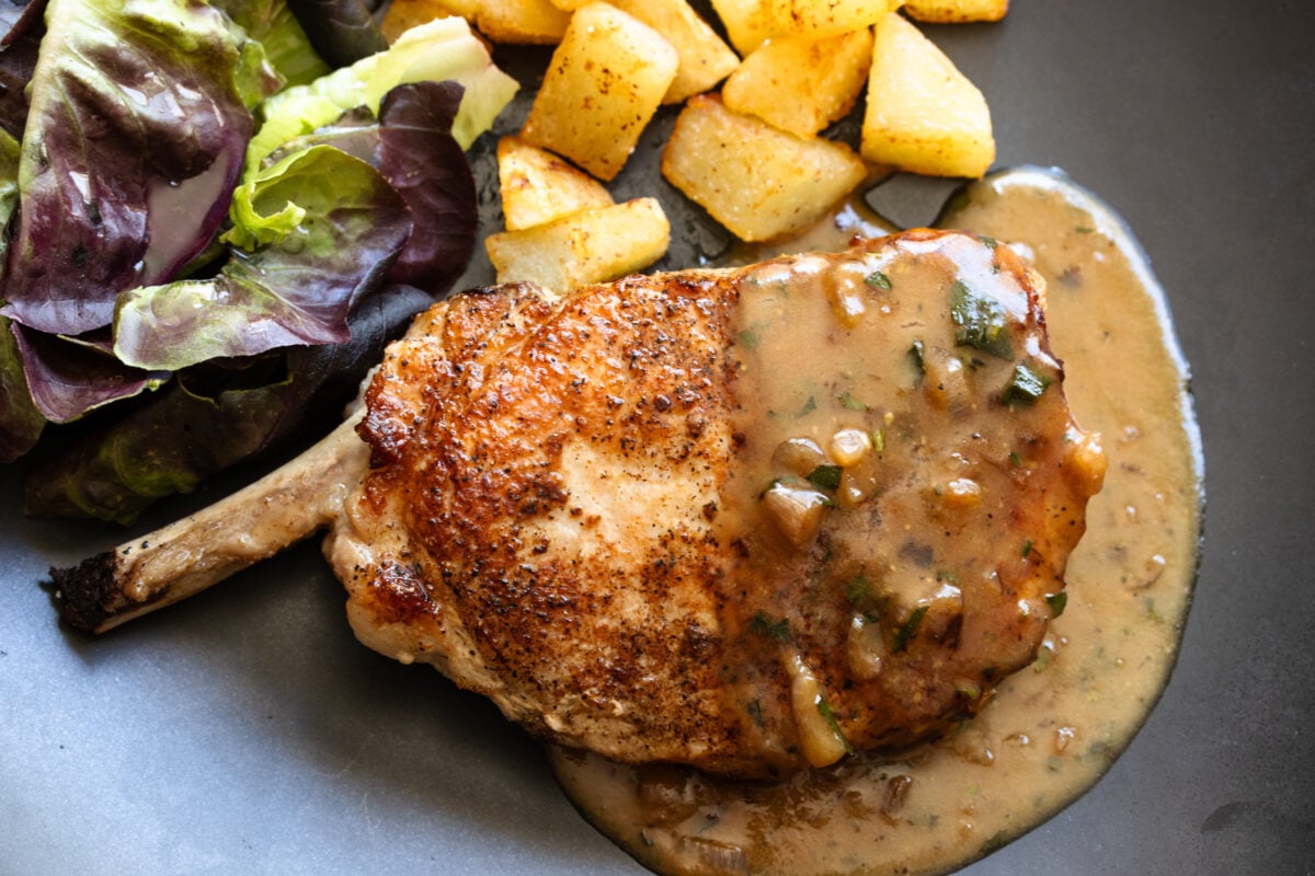 Cooked to a golden, pork chops are served with gravy over it.