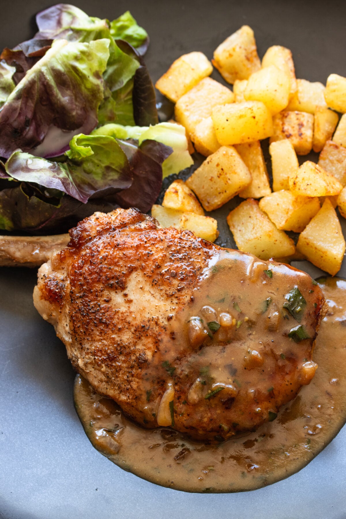 Pork Chops with Beer and Mustard Gravy served alongside potatoes and salad.