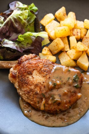 Pork Chops with Beer and Mustard Gravy served alongside potatoes and salad.