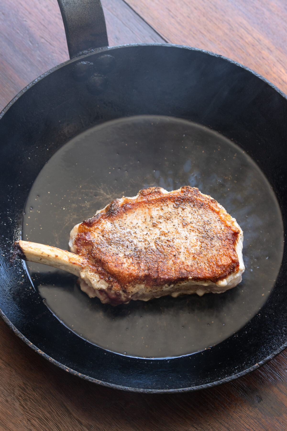 Perfectly seared pork chop to a golden in a skillet with olive oil.