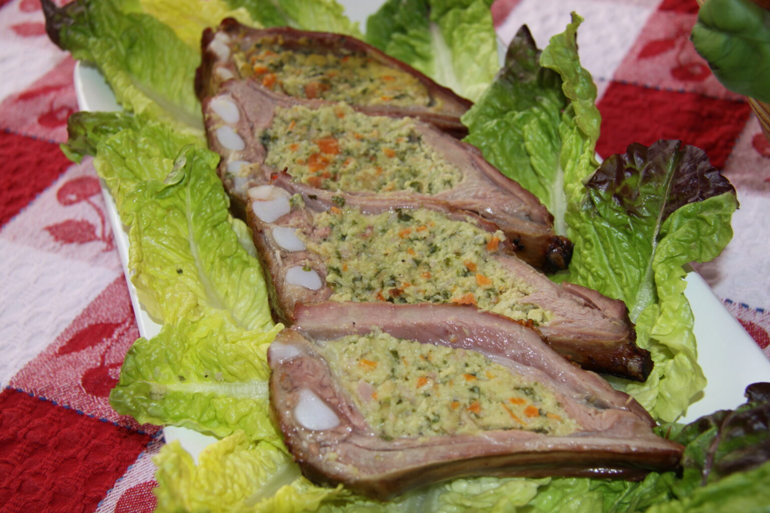 Cima sliced and served in a rectangular service plate with lettuce all around it. 