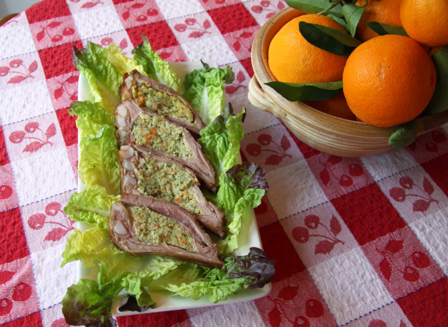 Sliced cima served over a bed of lettuce. Oranges are served alongside.