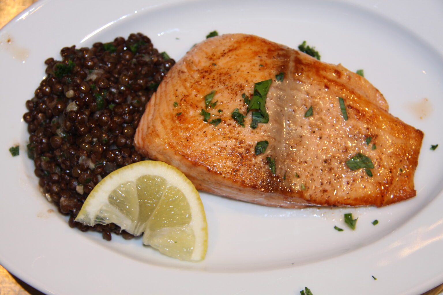 salmon with lentils served in a white dish.