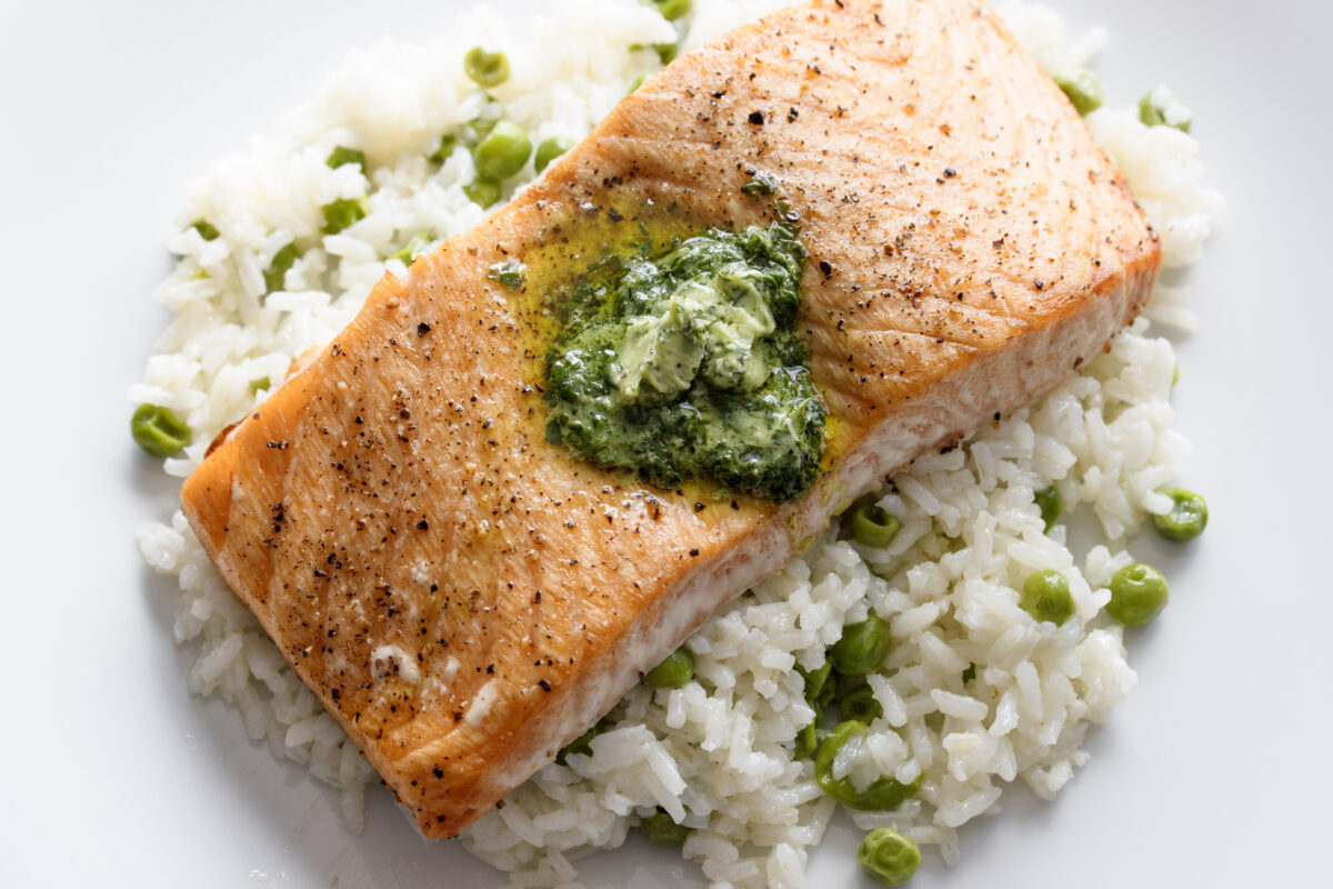 Baked salmon with herb butter served over a bed of white rice and peas. 