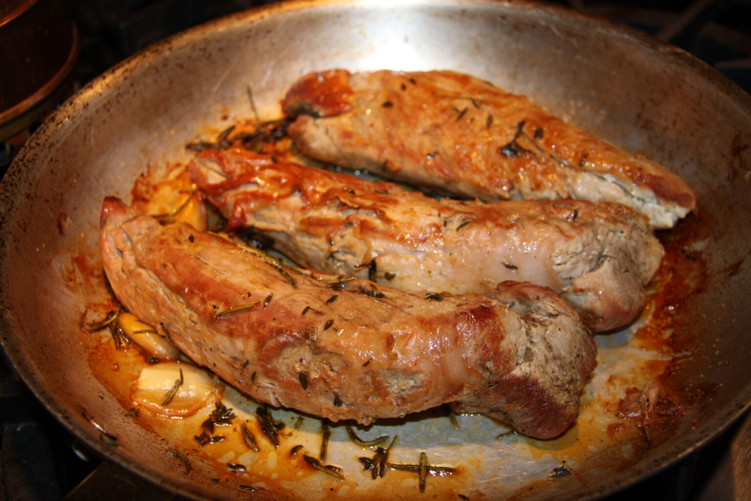 The tenderloin searing in the skillet.