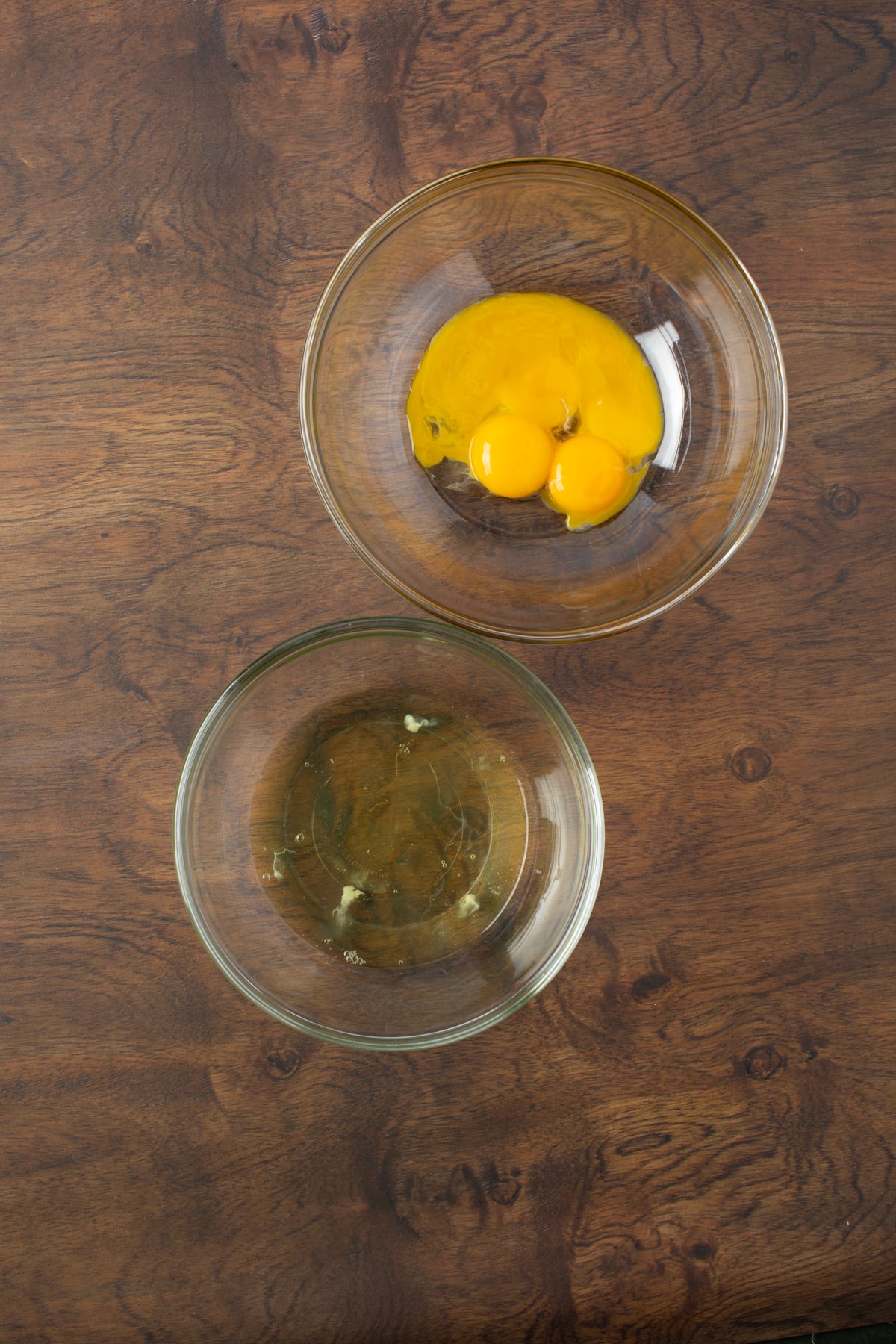 Egg yolks and egg white are separated and placed into mixing bowls.