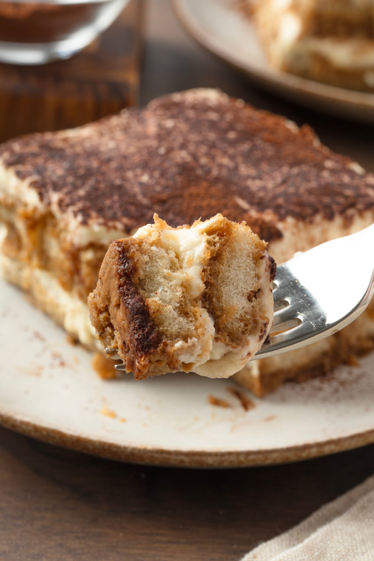 A close up of a forkful of the tiramisu where. you can see the layers of savoiardi and mascarpone cream. 