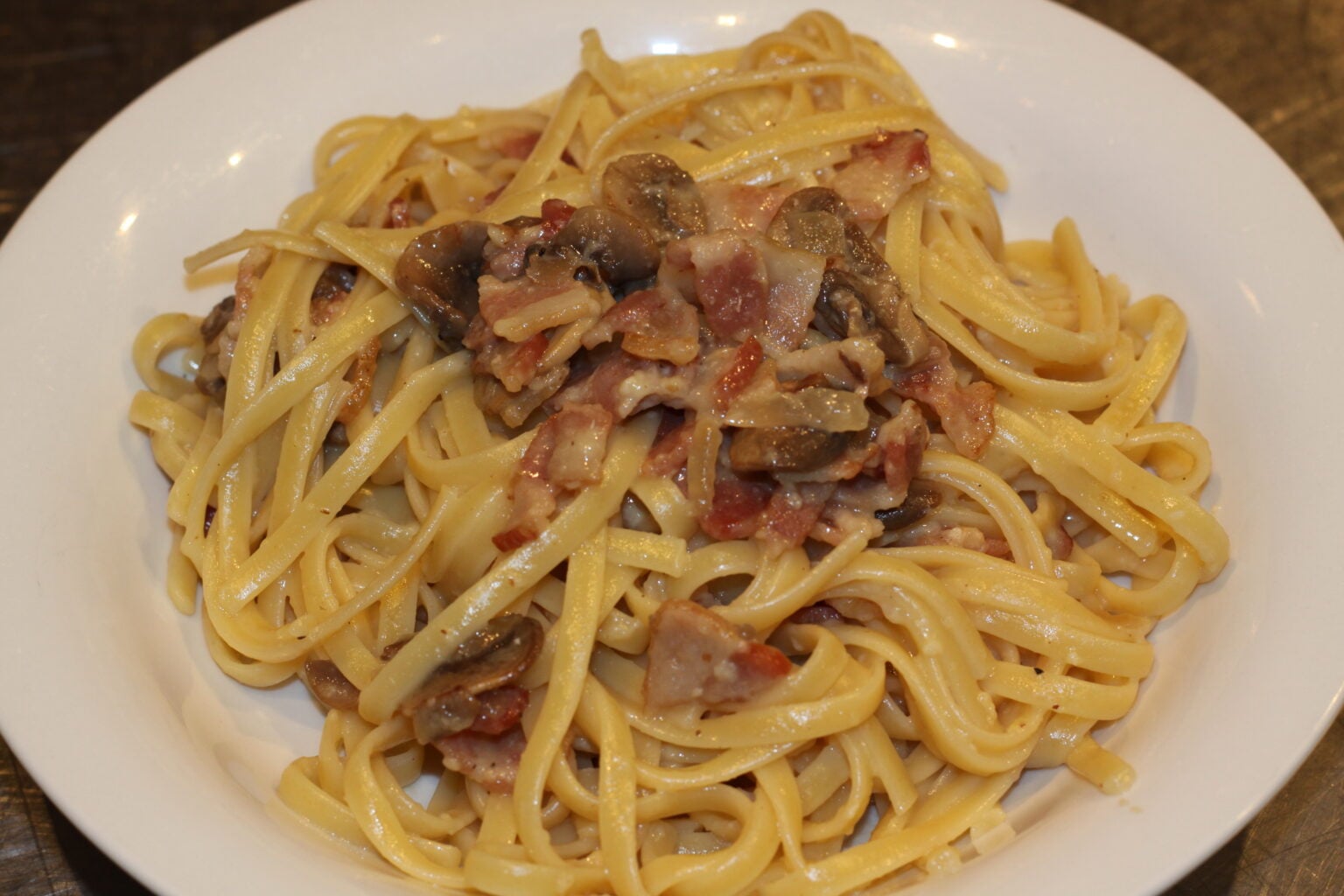 Linguine pasta with mushrooms alla carbonara in a white serving plate