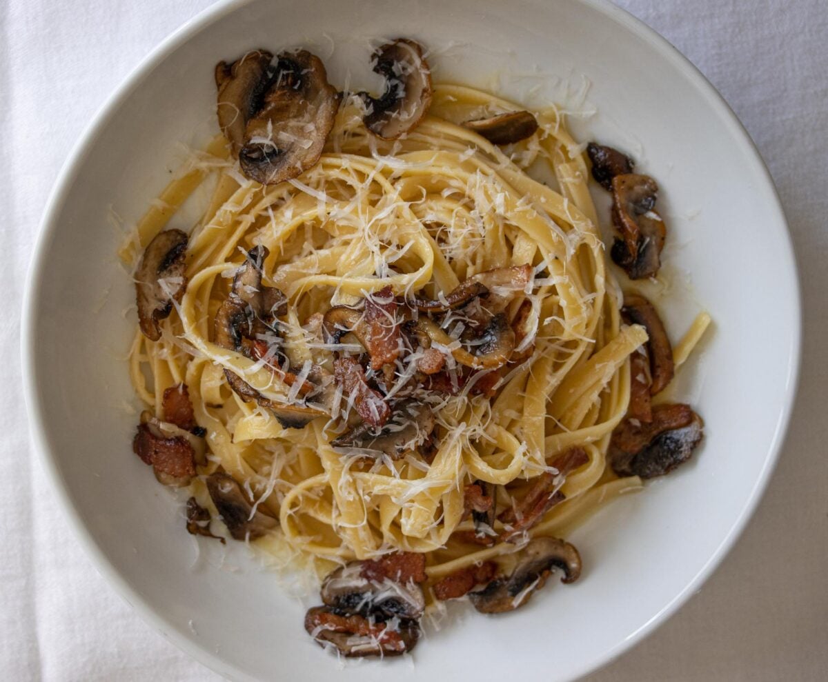 Close up of the linguine carbonara with crispy mushrooms served in a white pasta dish.