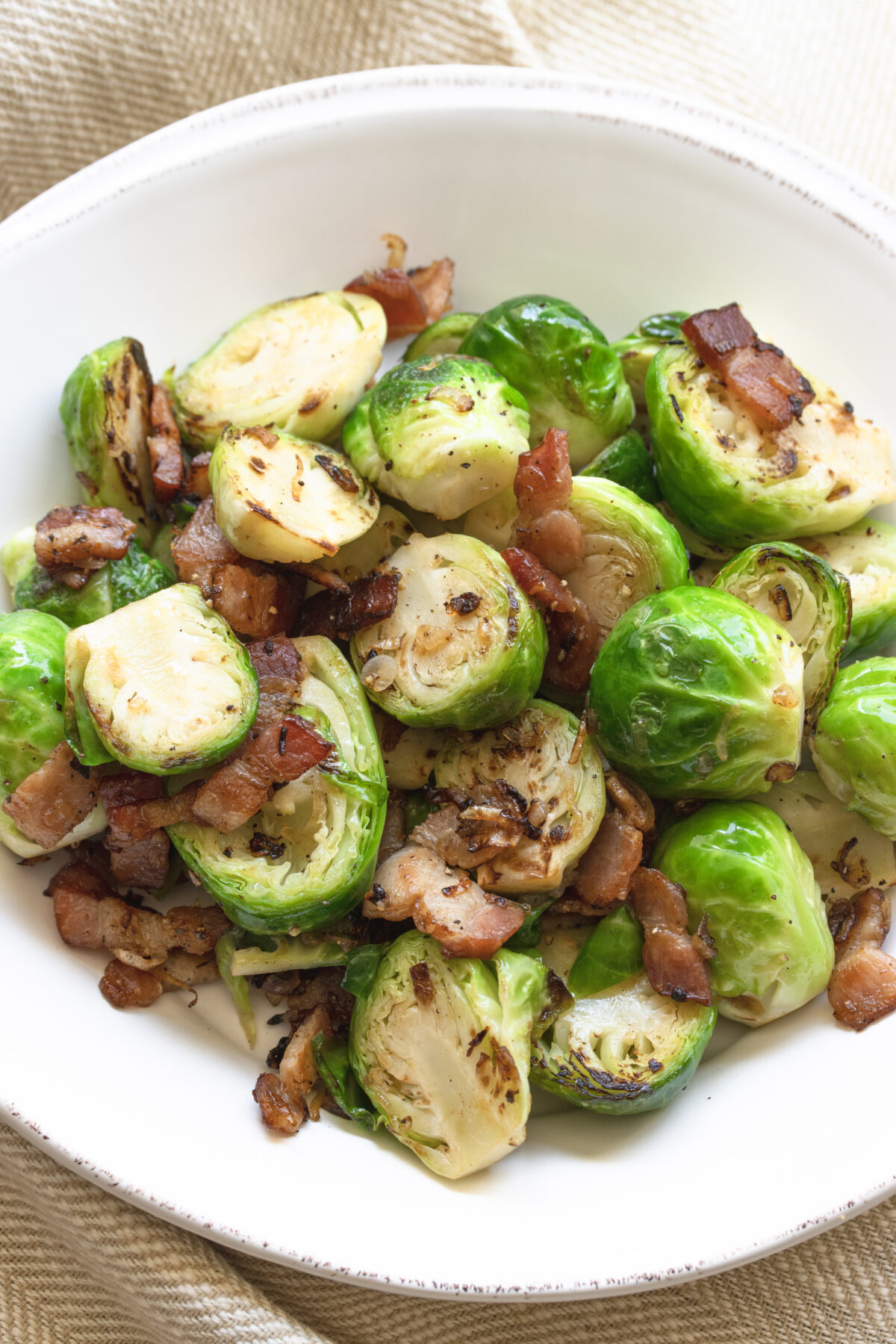 Brussels Sprouts with Bacon and Shallots served in a round white serving dish. 