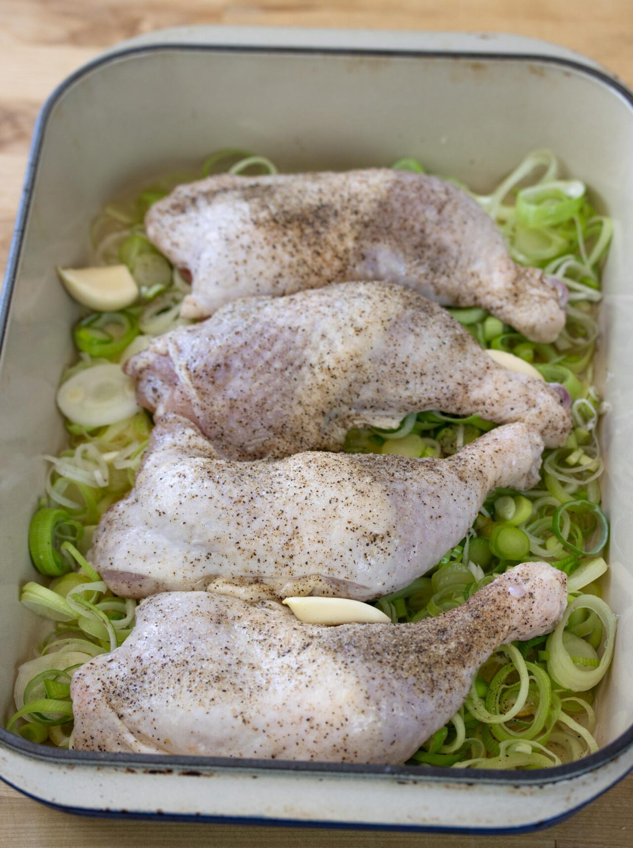 The chicken has been placed on top of the leeks. 
