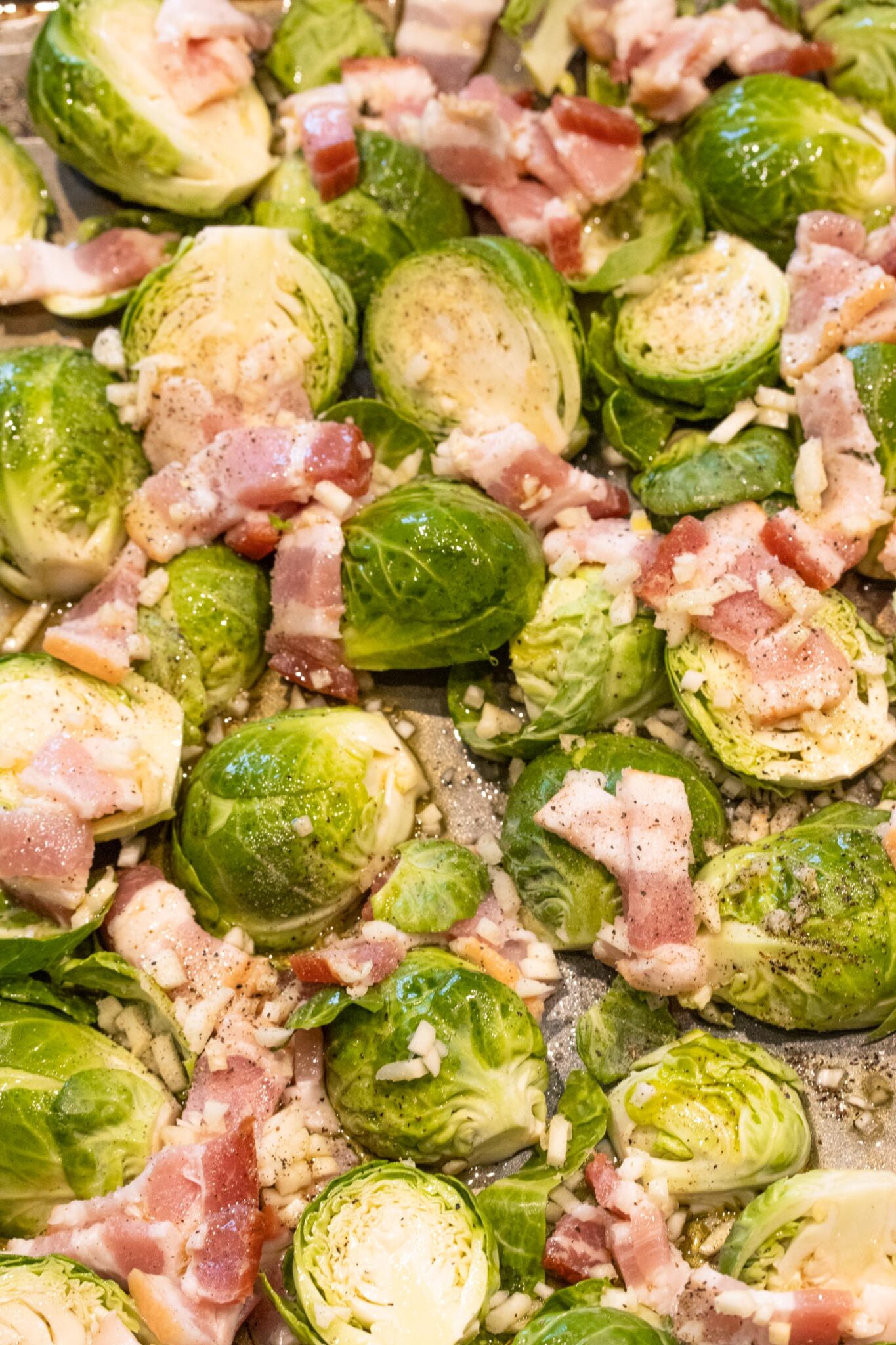Brussels sprouts sliced with bacon pieces in a pan ready to be cooked.