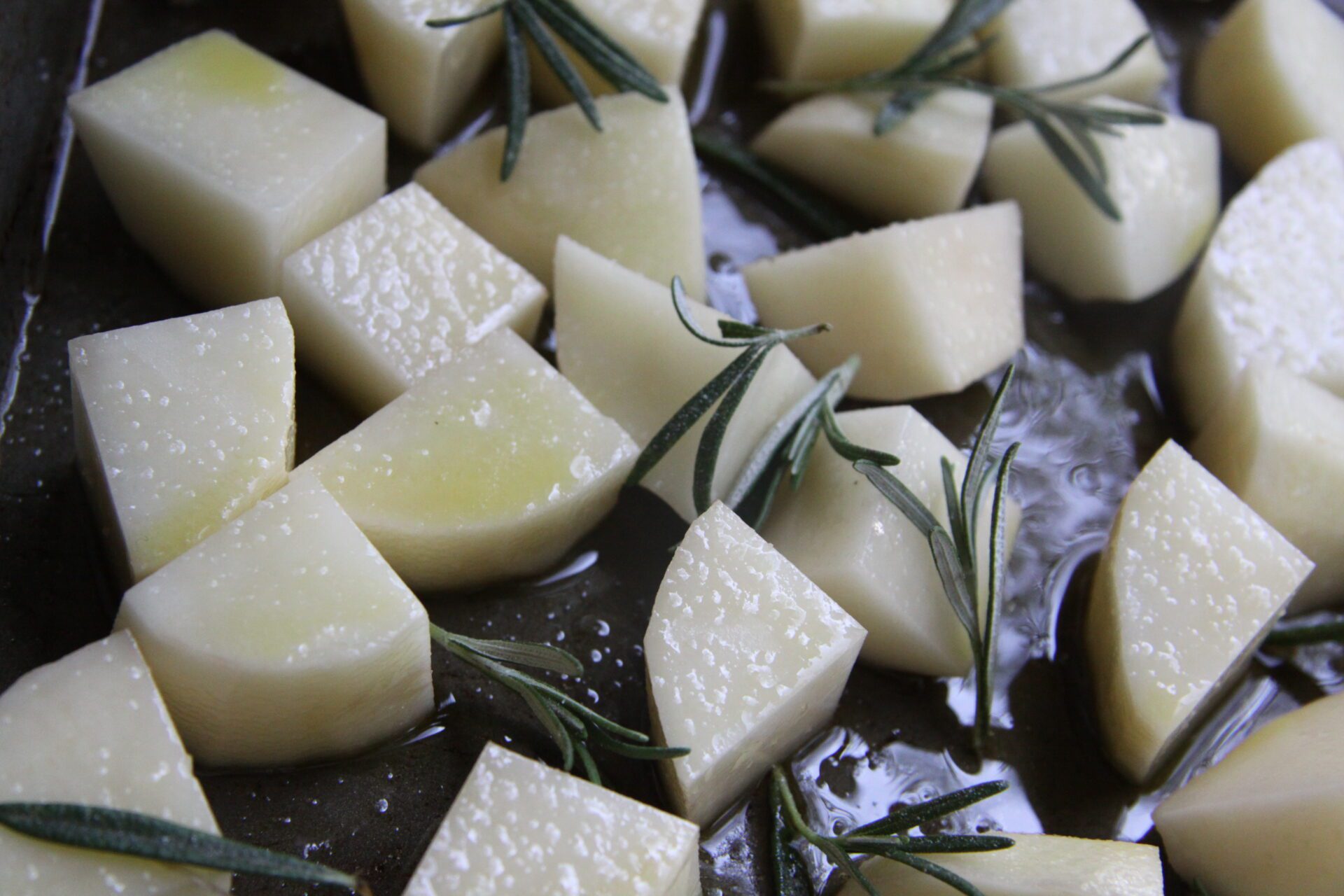 cut potatoes with rosemary on a cookie sheet