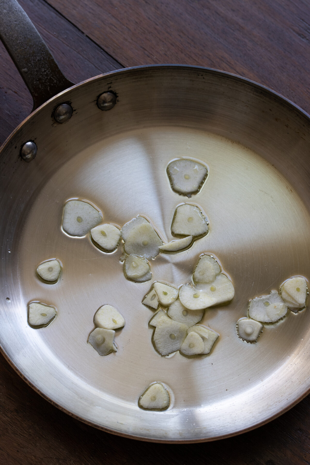 Garlic slivers cooking gently with the olive oil in a large skillet.