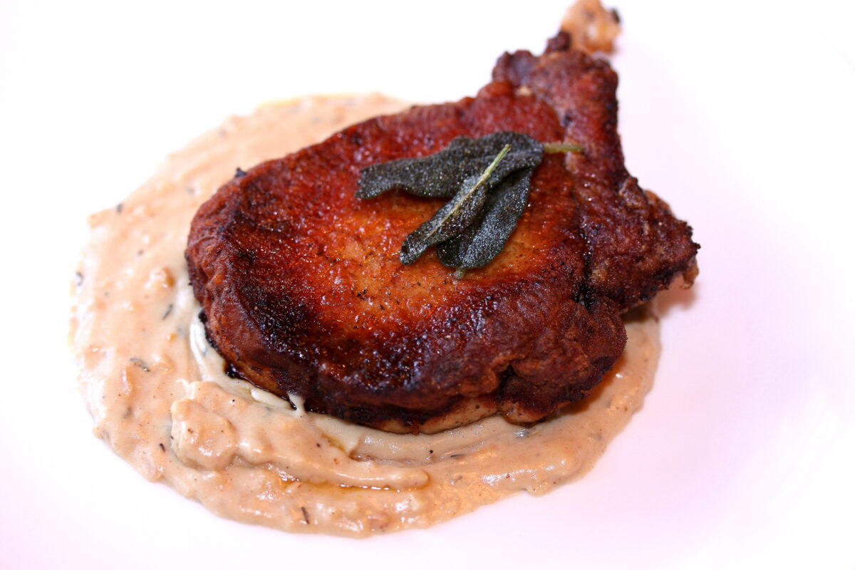 Skillet pork chops iwth browned butter sage on a white plate.