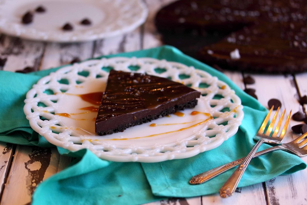 Dark chocolate ganache tart slice served on a white plate