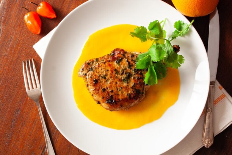 Pork chops with habanero sauce served on a white dish.