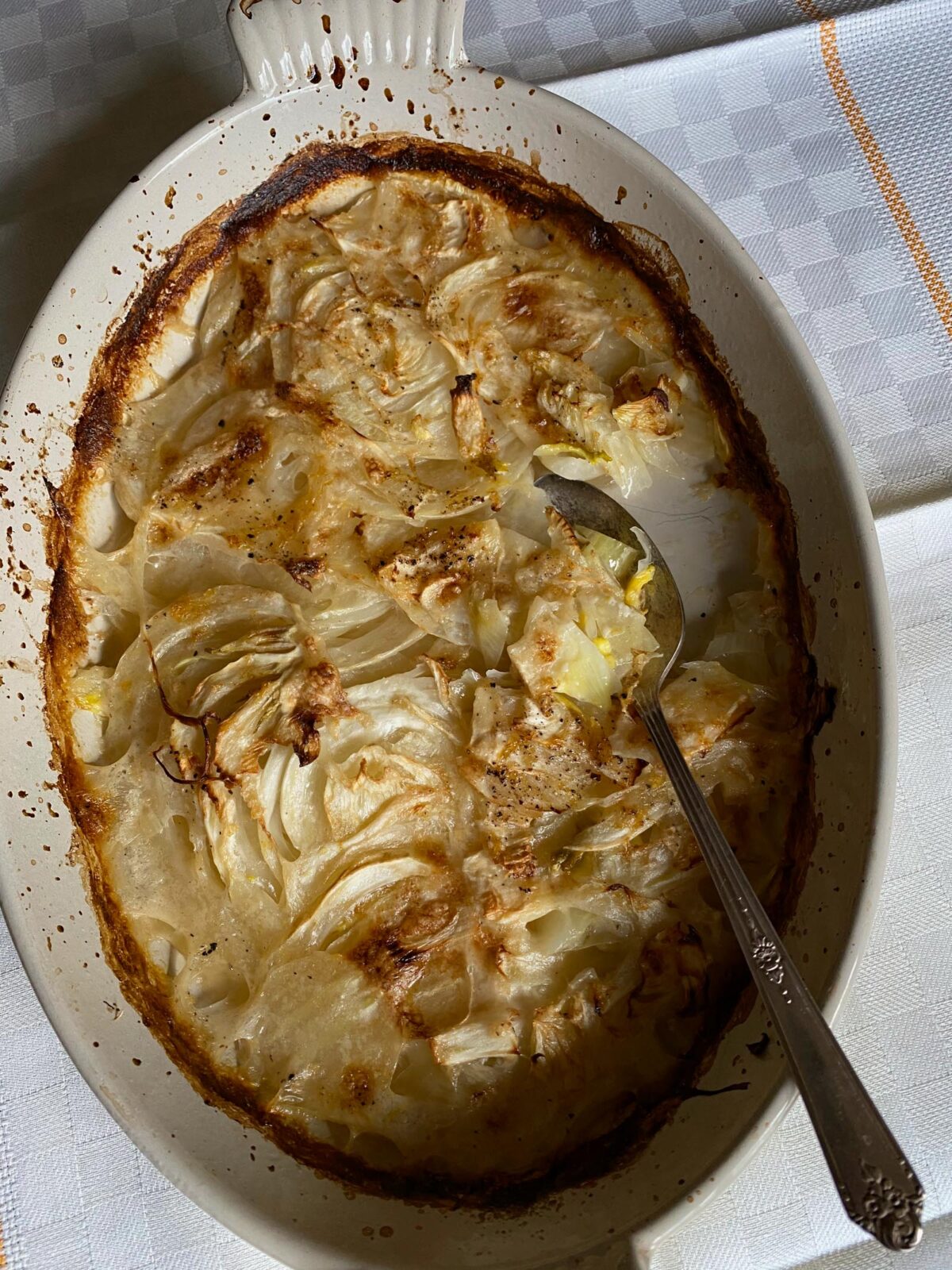 Fennel Gratin with coconut milk in a gratin dish with a spoon.