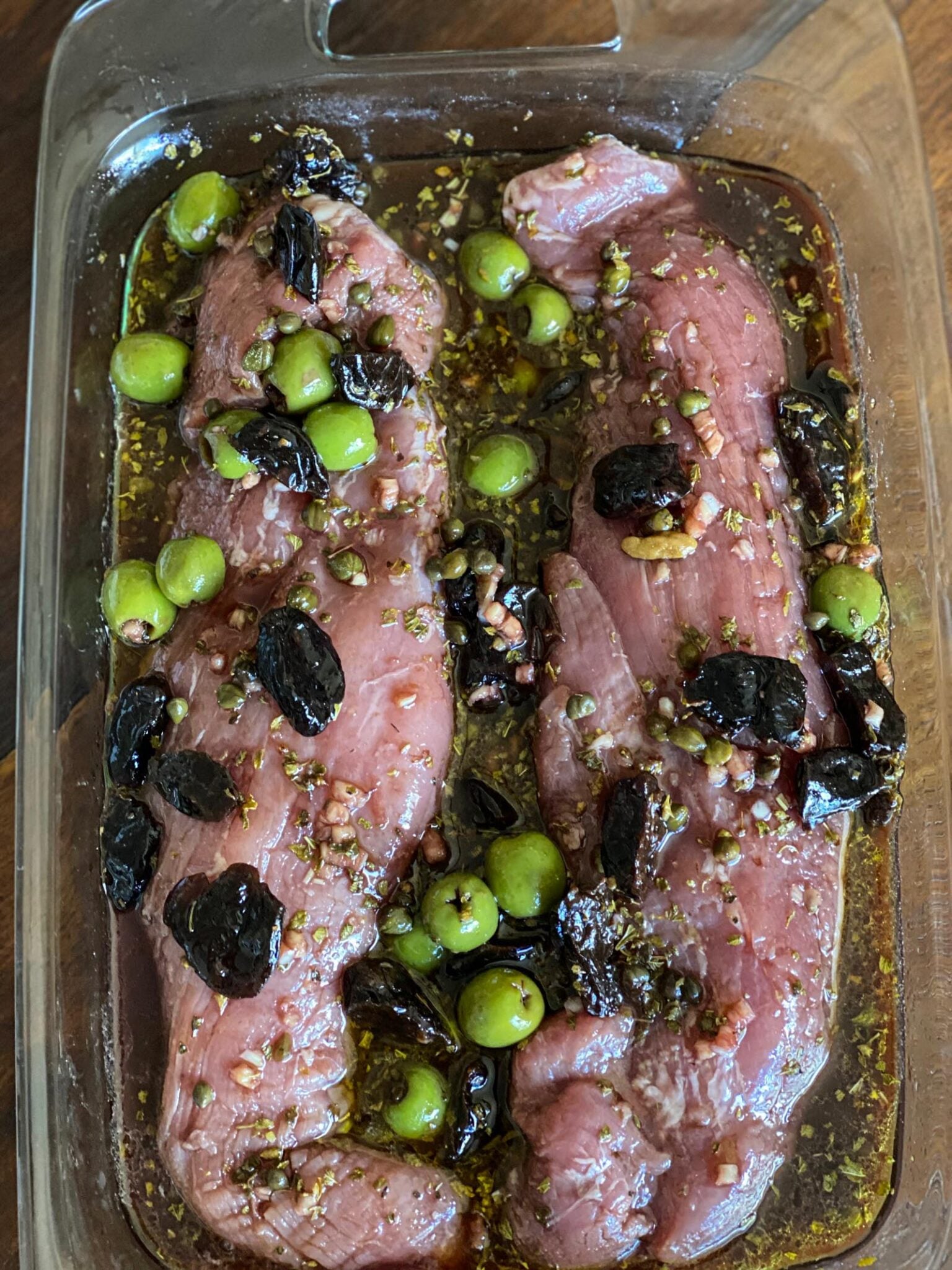 Mixing the wine, prunes, green olives, brown sugar, capers with the brine, red wine vinegar, oregano, garlic and some of the olive oil.