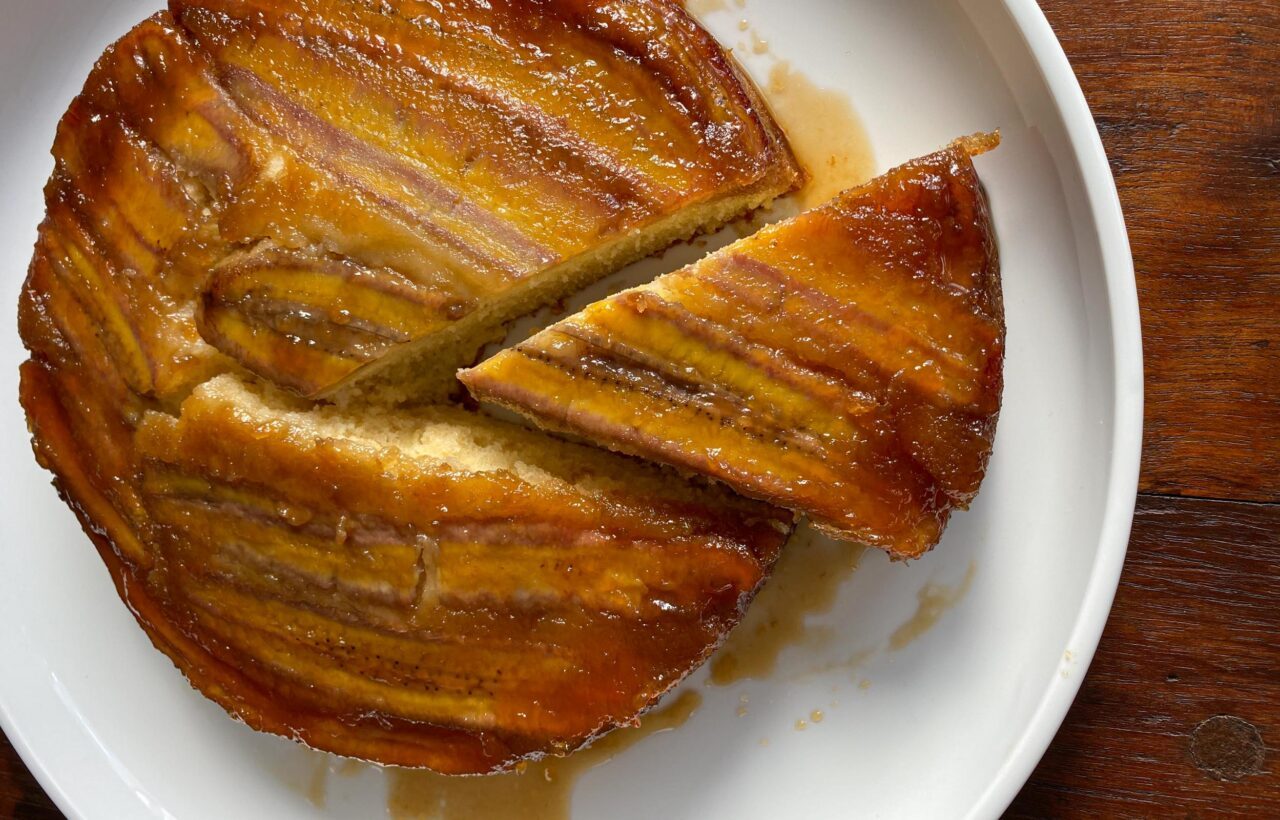 Banana Upside-Down Cake Banana Upside-Down Cake on a white plate with a slice out