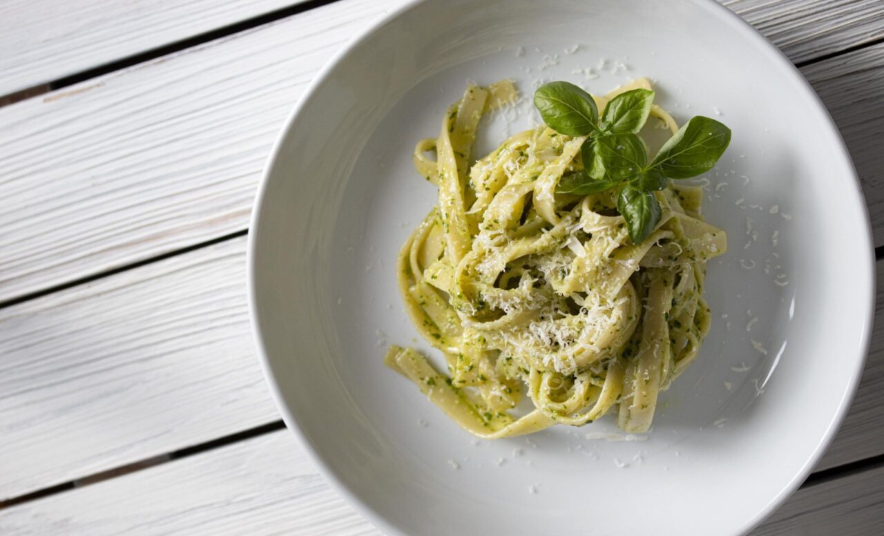 fettuccine al pesto genovese served in a white pasta dish.