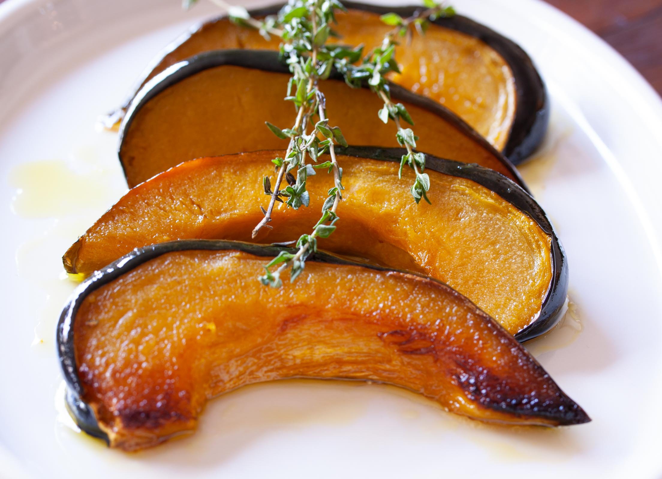 Green Acorn Squash With Honey Vinaigrette Roasted acorn squash with honey vinaigrette in a white serving plate.