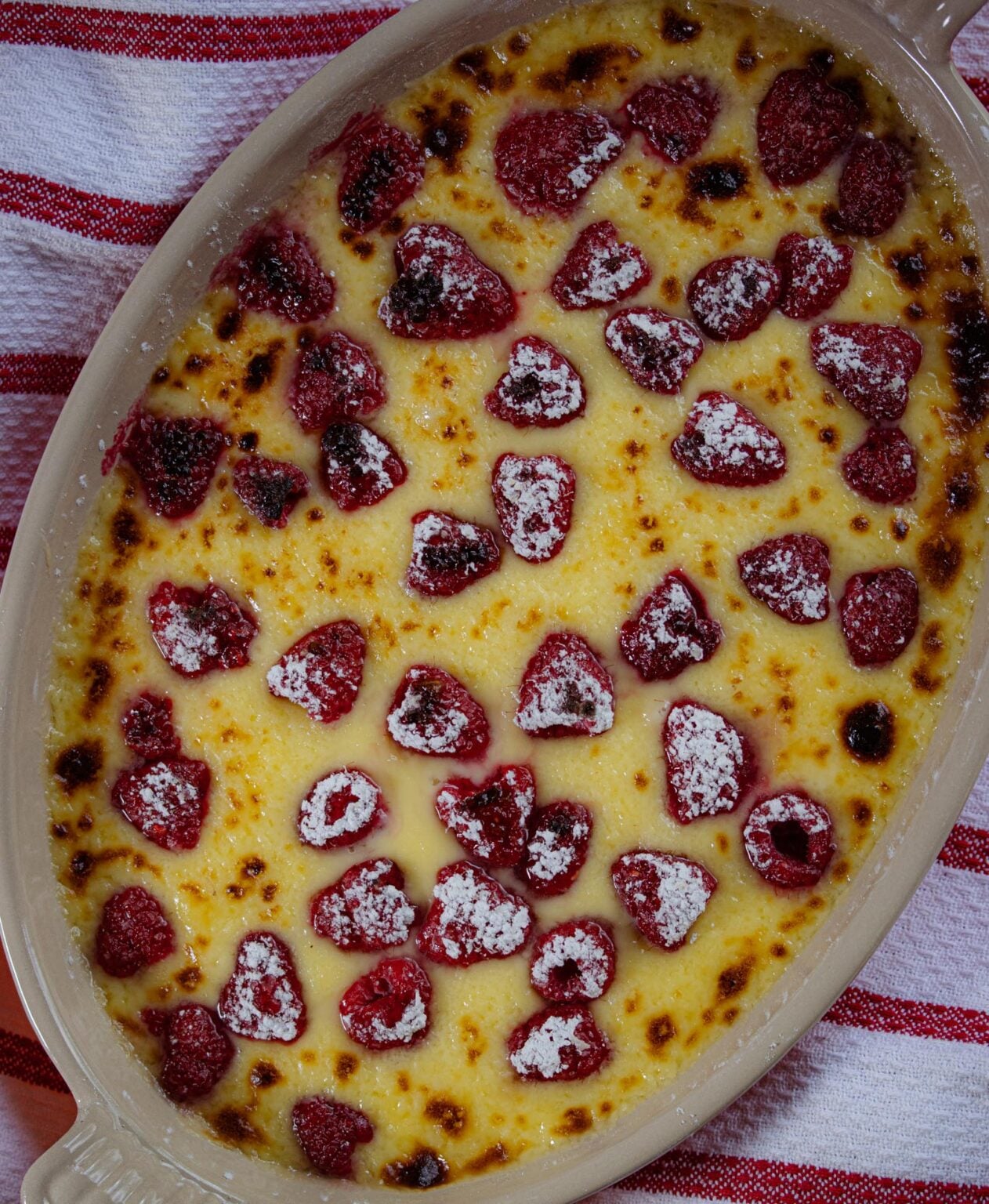 Raspberry gratin served in an oval gratin dish with powdered sugar sifter over it.