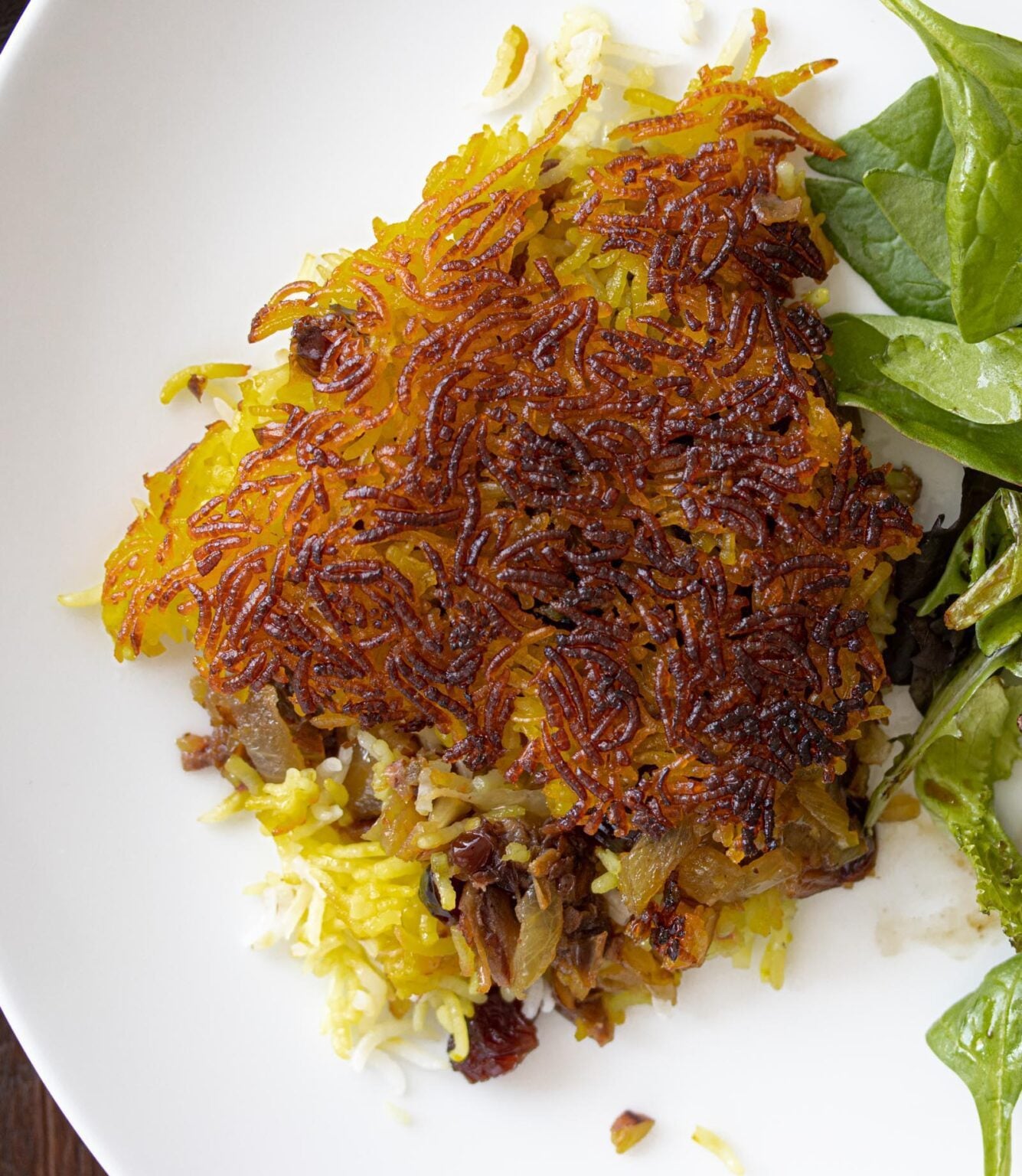 Saffron lemon chicken with Persian rice Persian rice with salad on a white plate.