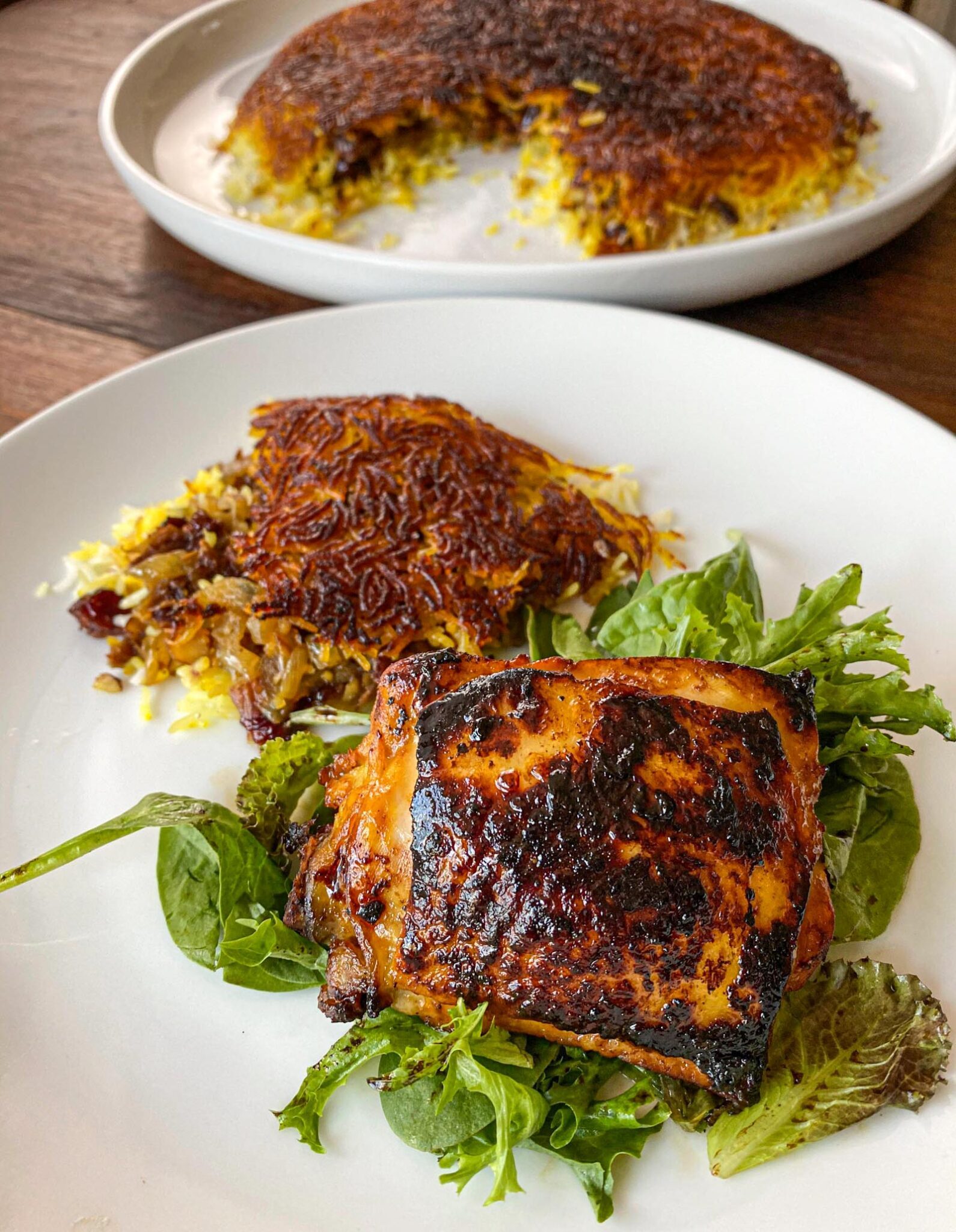 Saffron lemon chicken with Persian rice in a white serving plate.