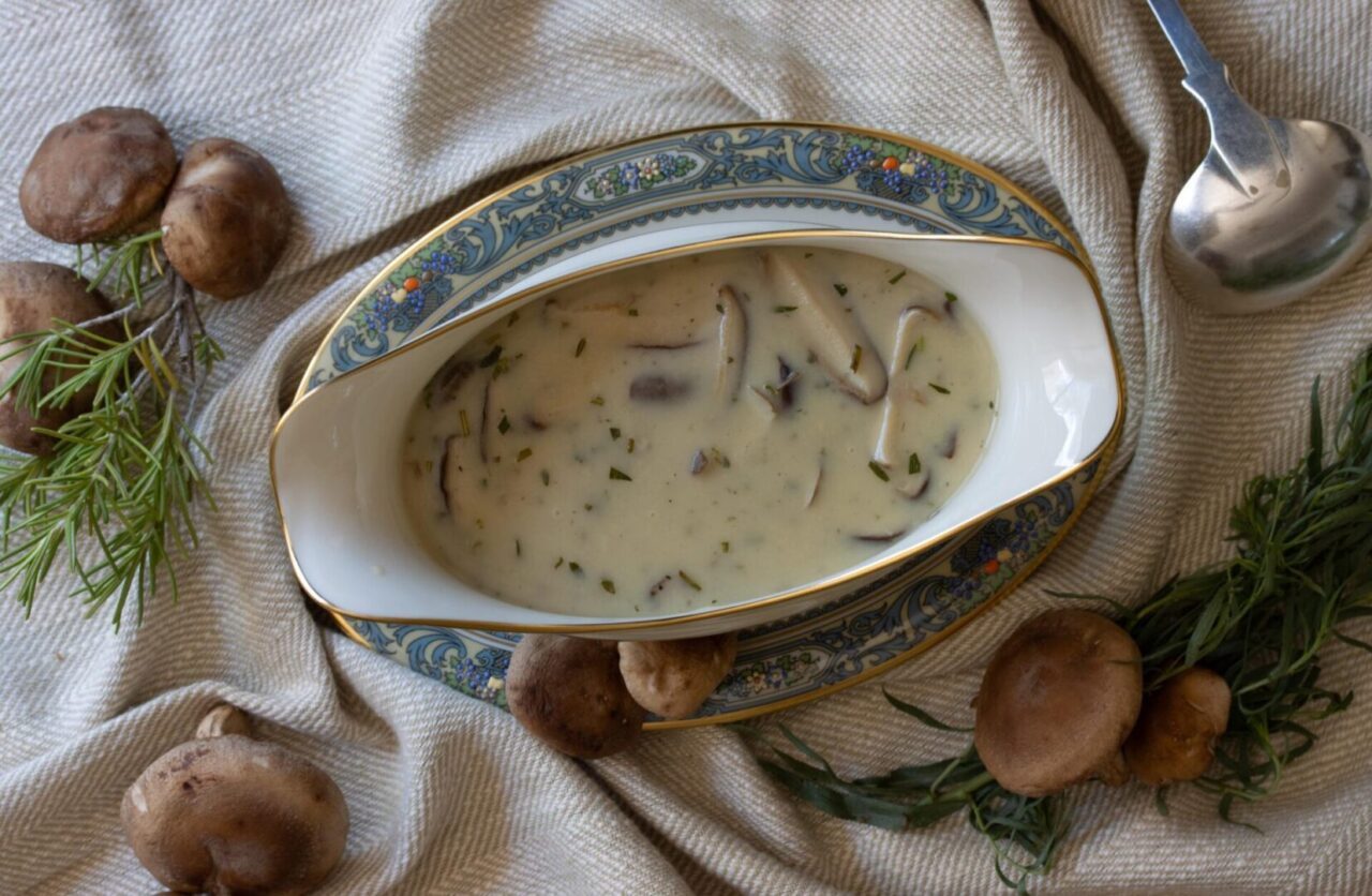 shiitake mushrooms gravy in gravy boat with ladle and decorative mushrooms around it