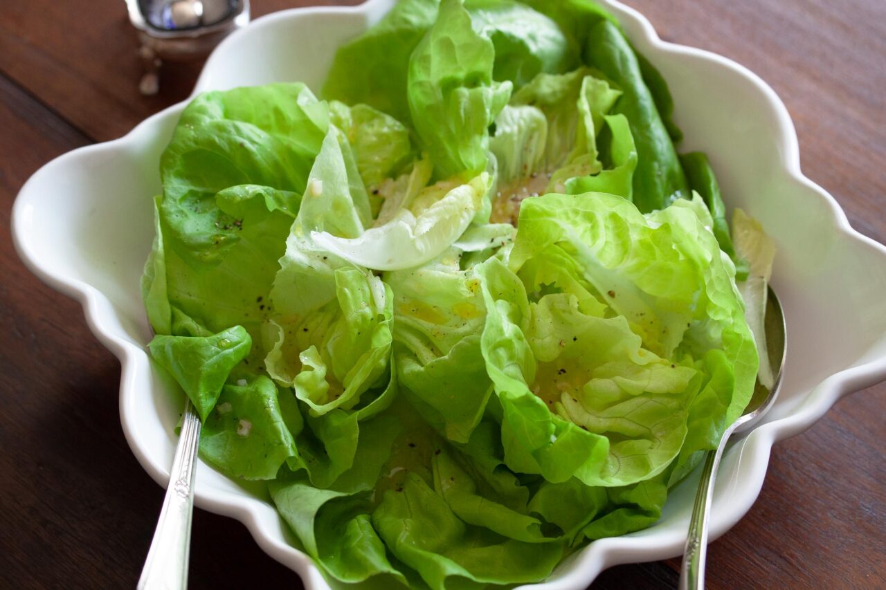 Butter Lettuce With Shallots Vinaigrette The salad served in a white bowl with servings forks.