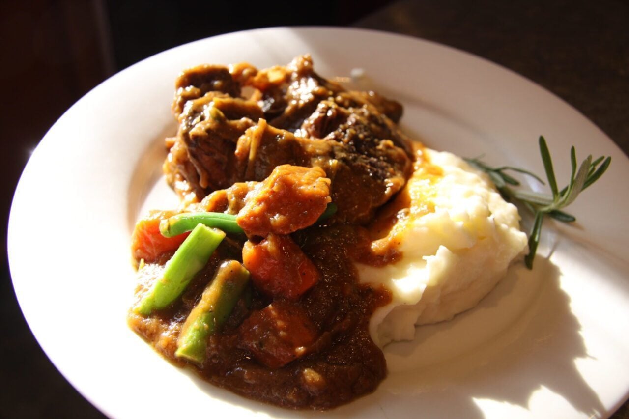 The finished recipe served with mashed potatoes on a white plate.
