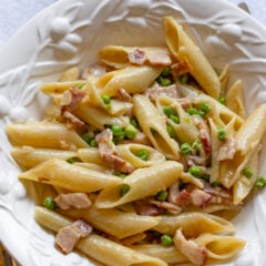 Penne Pasta with Peas and Bacon served in a white pasta plate.