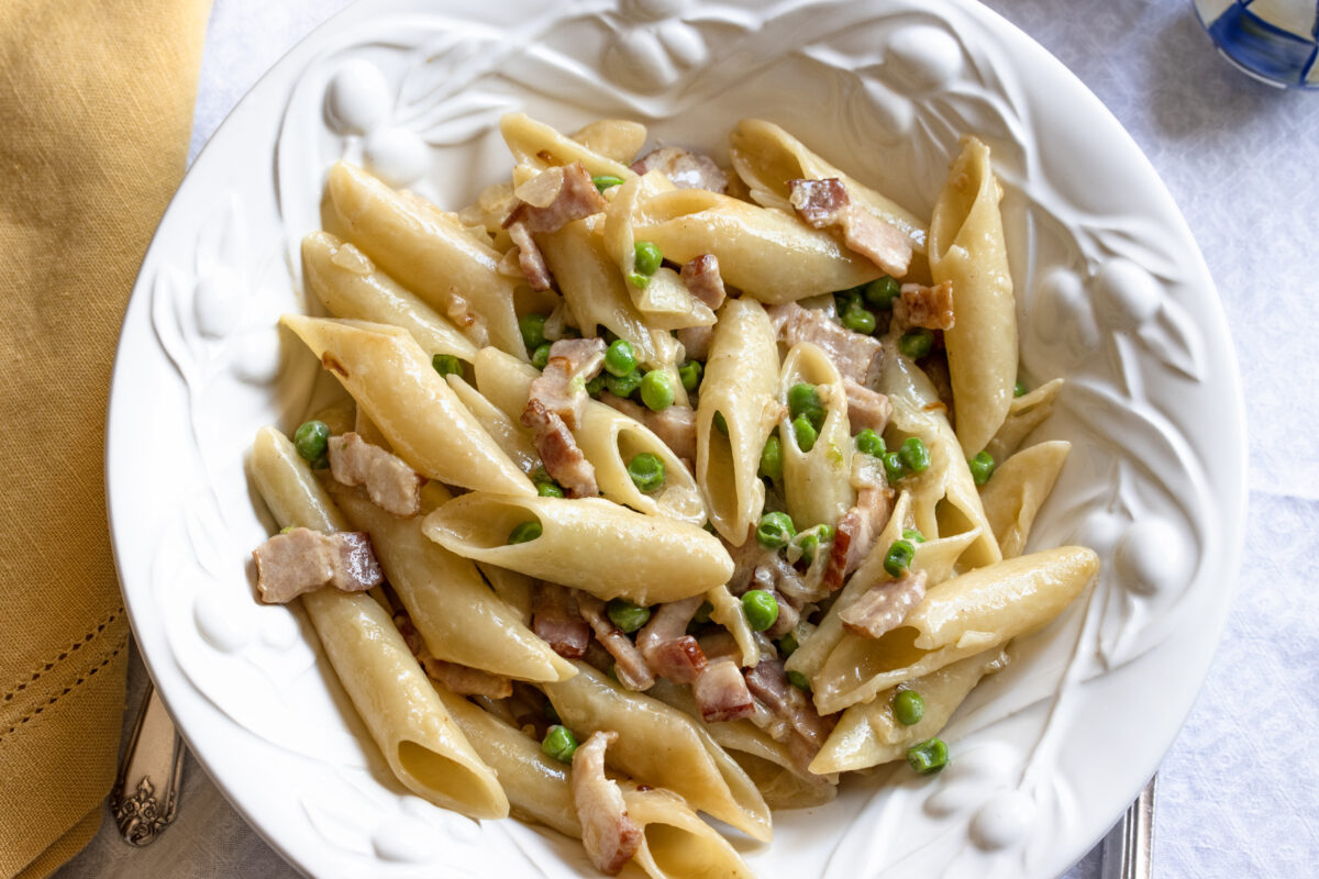 penne pasta, peas and bacon Finished dish of penne pasta with creamy pease and bacon.
