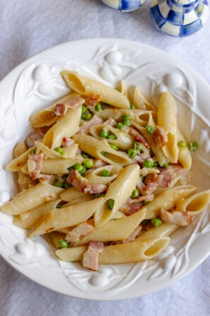 Penne Pasta with Peas and Bacon served in a white pasta plate.