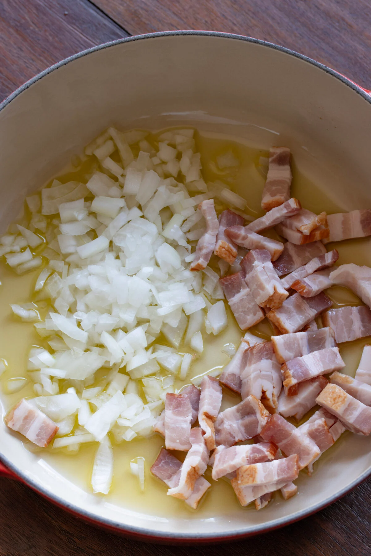 Chopped onion and bacon pieces are added to the skillet to be cooked.