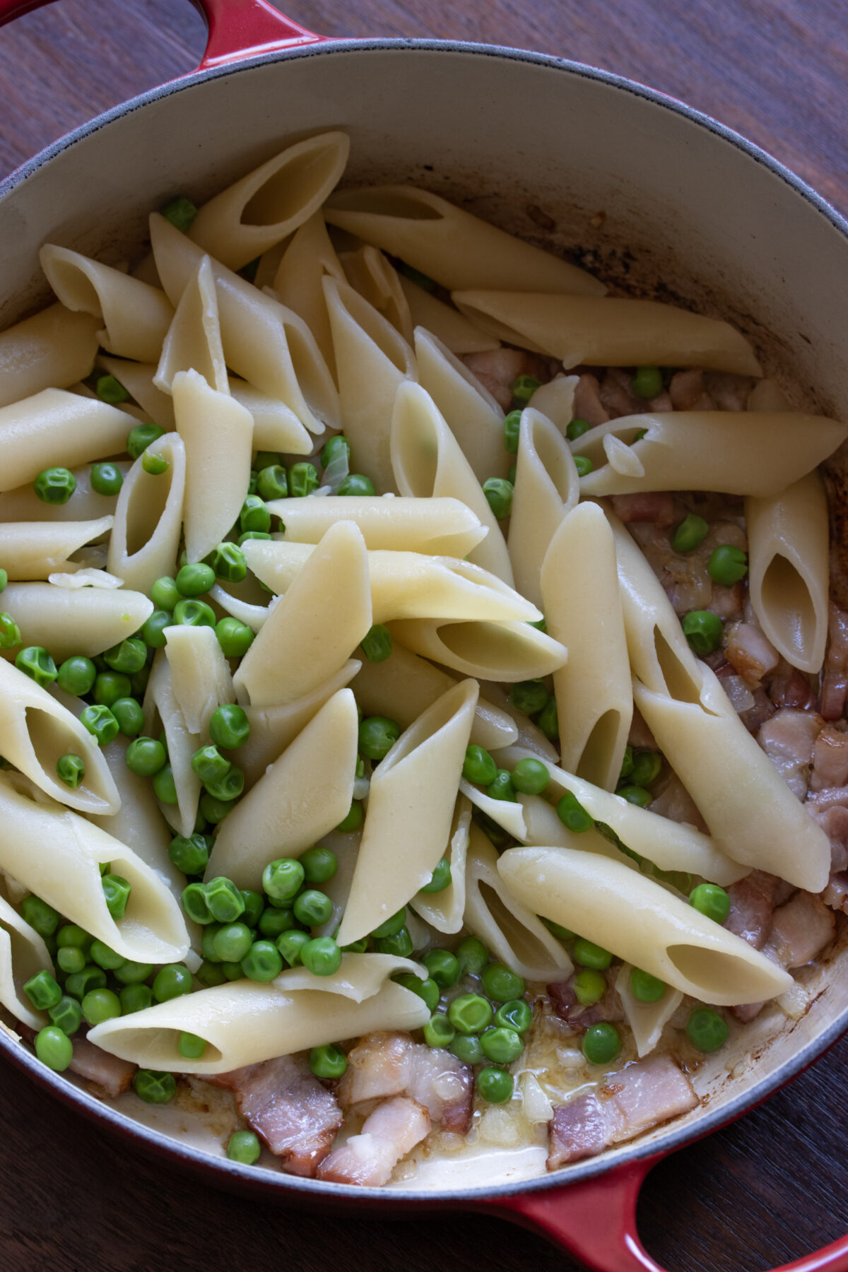 Cooked pasta is added to the bacon onion skillet.