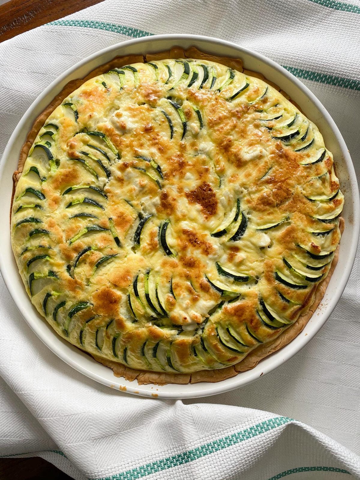Zucchini feta quiche served in a round baking dish. 