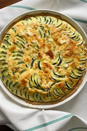 Zucchini feta quiche served on a white baking dish.