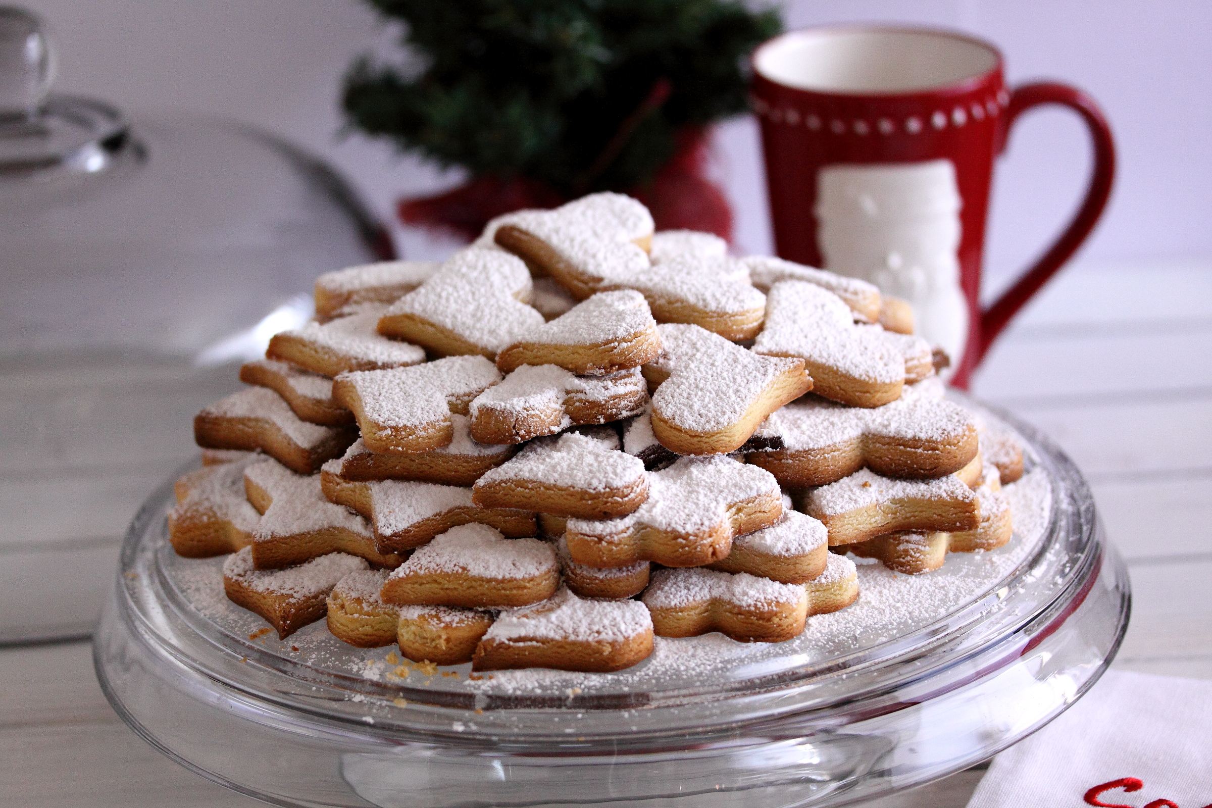 Canestreletti or Canestrelli Canestrelli Cookies - Italian Shortbread Cookies with Lemon served on a glass cake plate with a mug on the background.