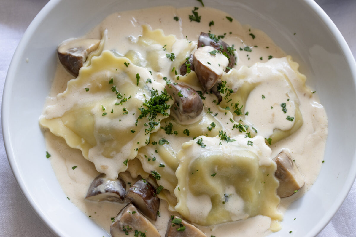 Ravioli with mushrooms and cream Cooked ravioli placed into pasta bowls and mushroom sauce poured over them.
