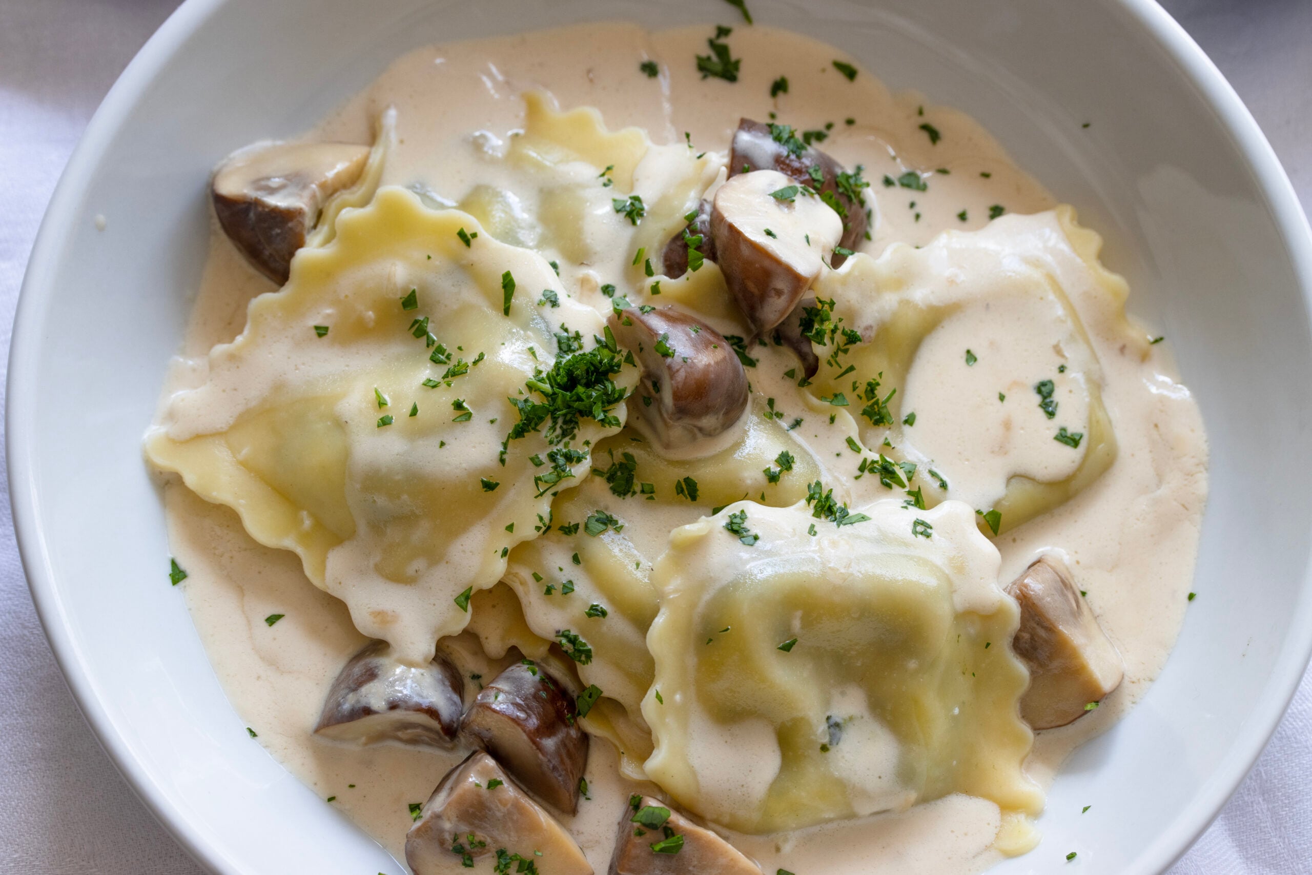 Ravioli with mushrooms and cream Cooked ravioli placed into pasta bowls and mushroom sauce poured over them.