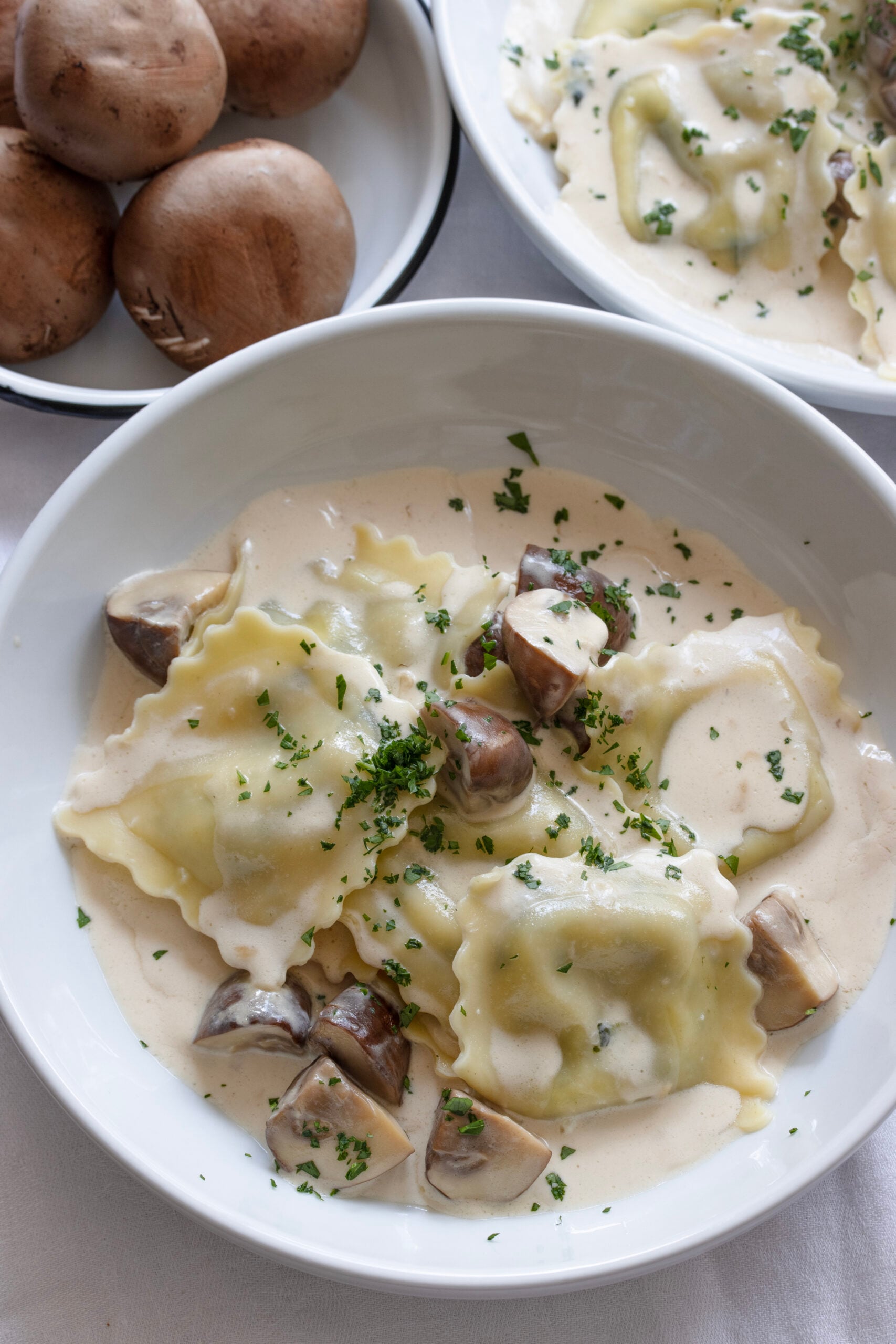 Ravioli with mushrooms and cream Ravioli with creamy mushroom sauce served into bowls and served with optional chopped parsley.