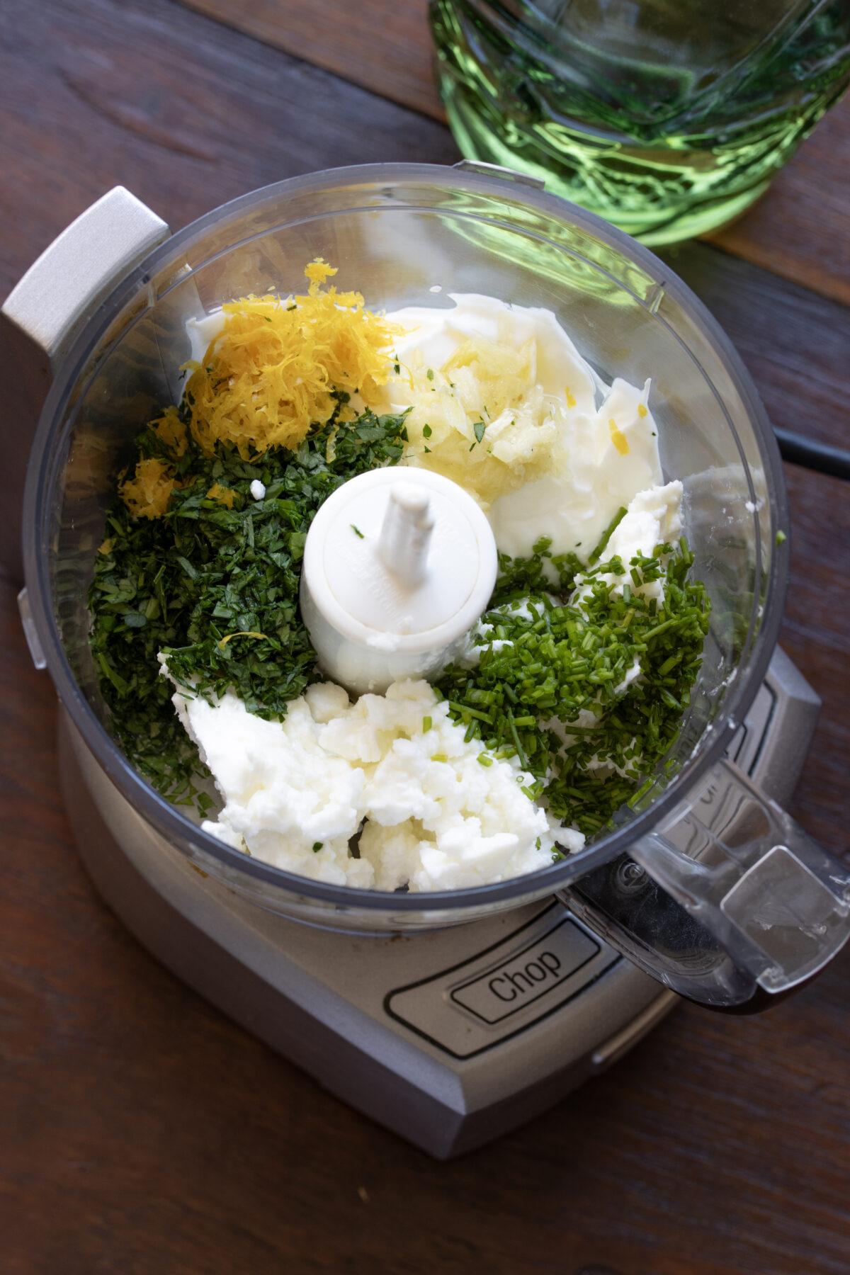 All chopped herbs with feta and yogurt in a food processor to be blended.