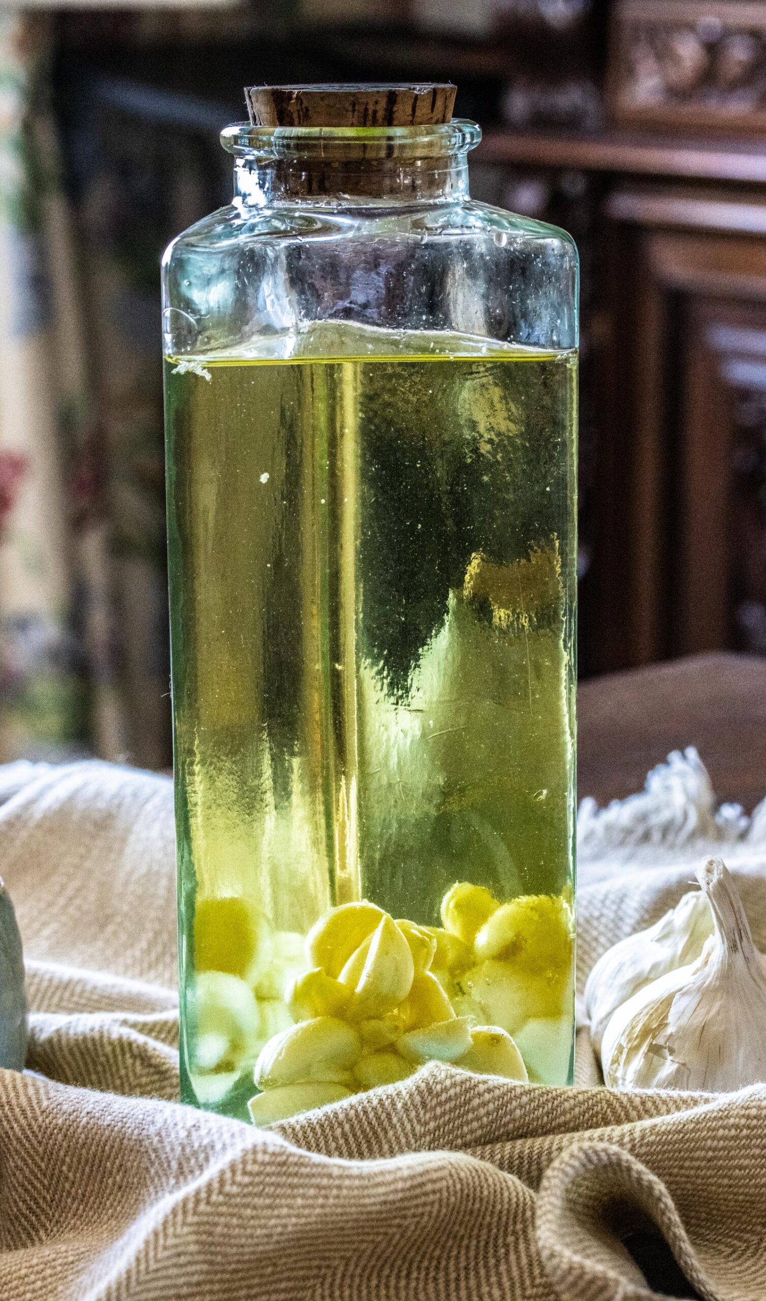 The oil in a glass bottle with pieces of garlic at the bottom. 