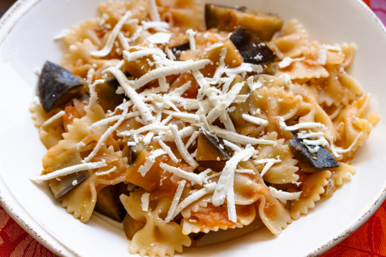 Eggplant pasta served in a white pasta dish with lots of pecorino romano.