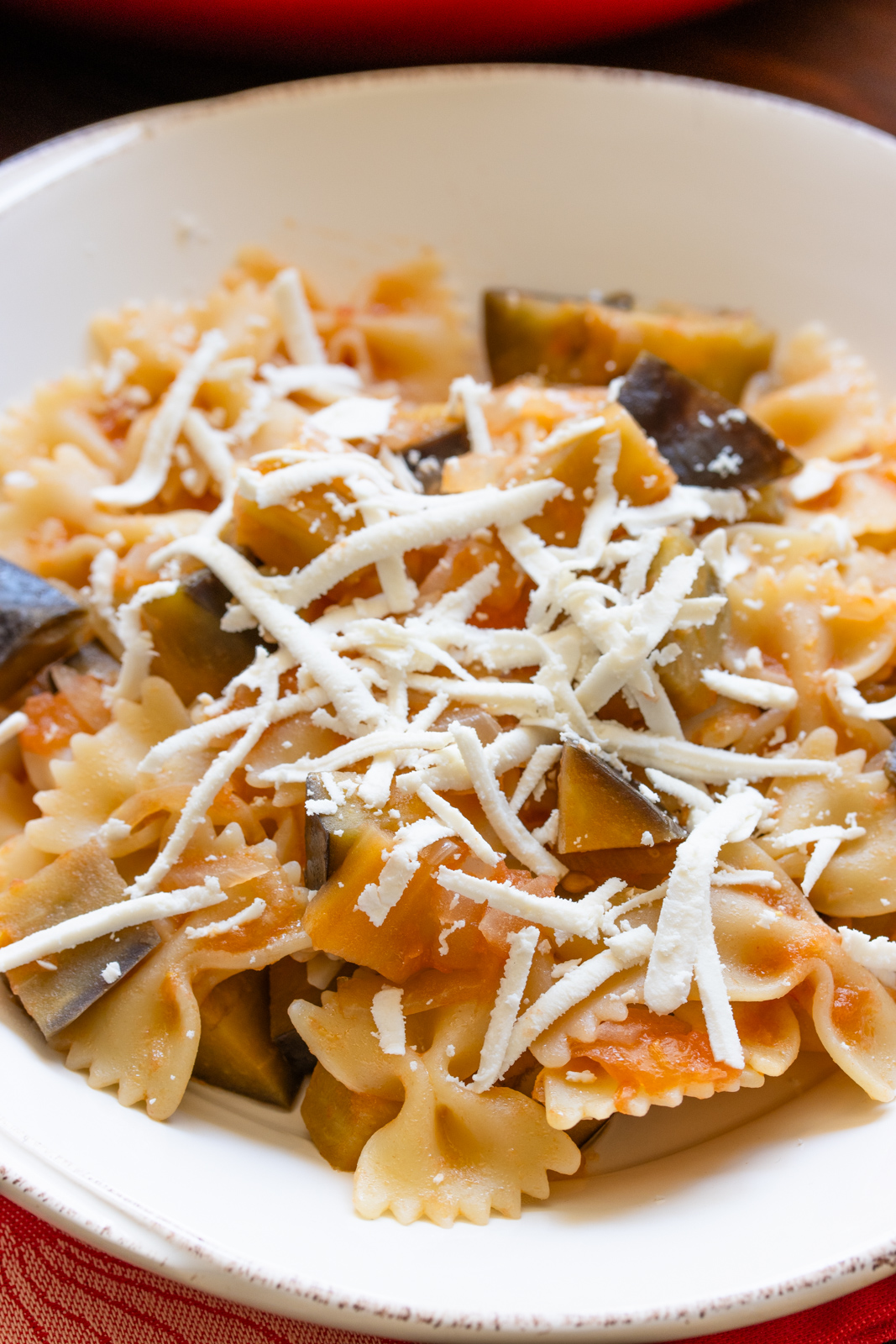 Eggplant, Pasta And Ricotta Salata Pasta alla Norma served with lots of ricotta salata in a white plate.