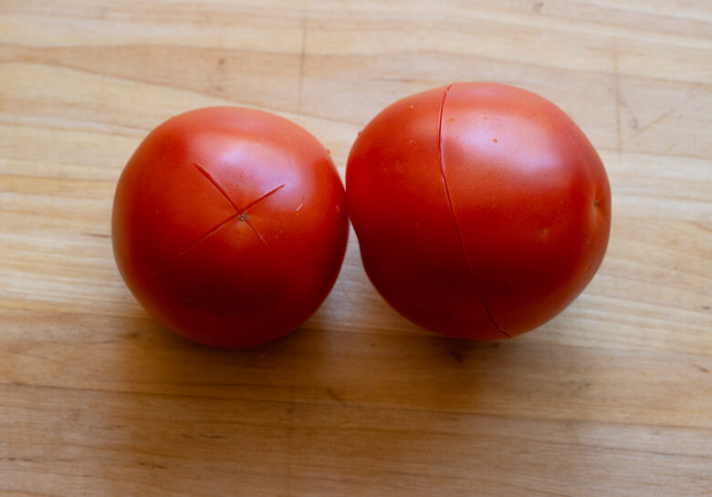 Tomatoes scored at teh bottom with an X and around them prior to blanching them.