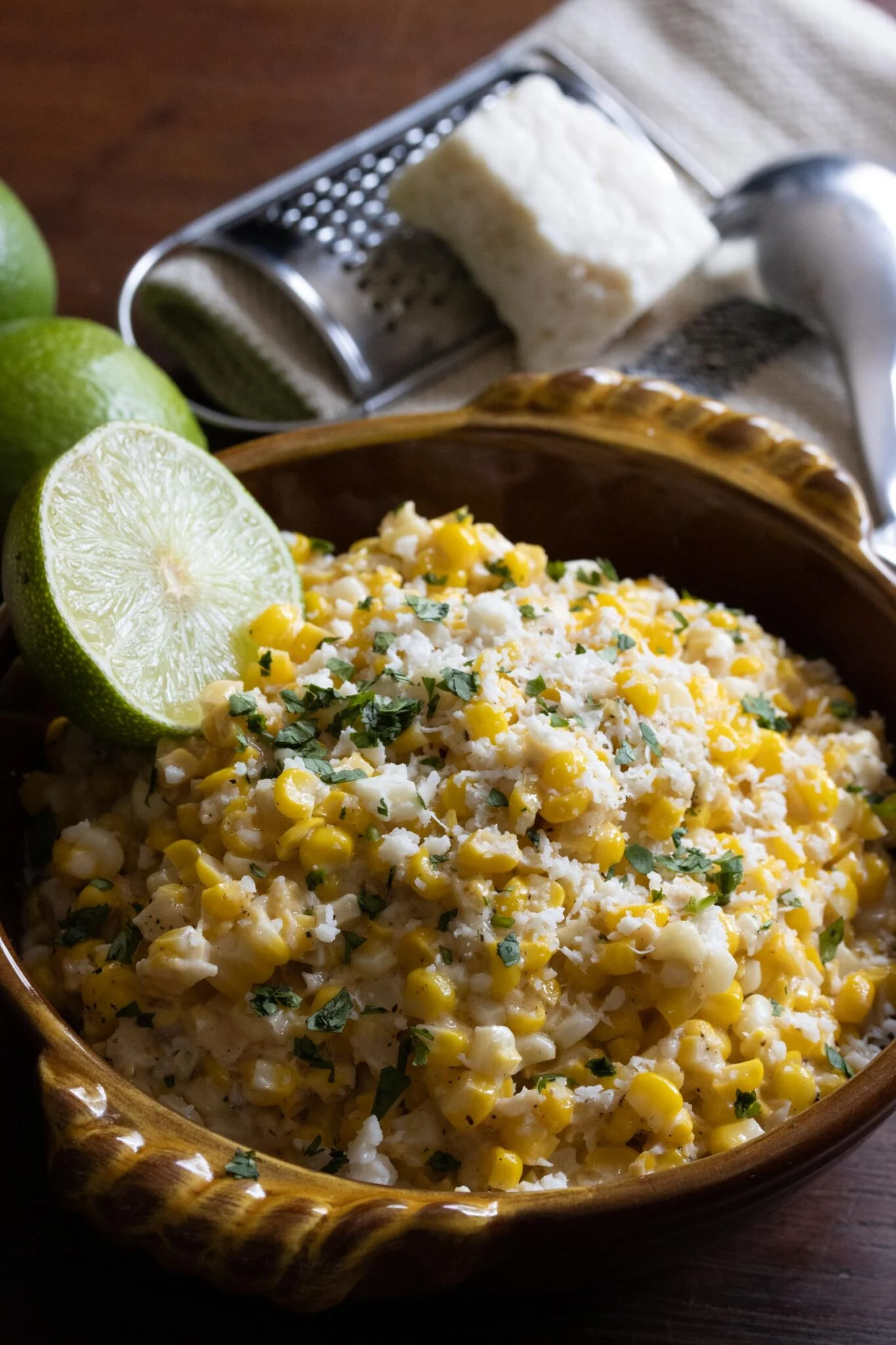 Elote elote Mexican street corn served in a mexican terracotta bowl with a wedge of lime.